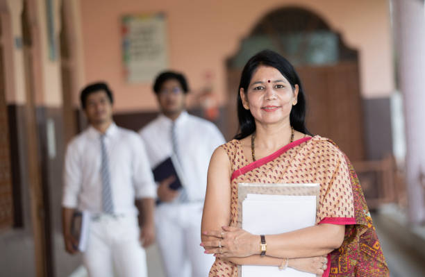 Confident smiling Indian school teacher with students in background